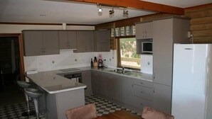 Eine kompakte Küche mit grauen Schränken, einer zentralen Kochinsel, einer Mikrowelle und einem Kühlschrank.