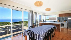 Une salle à manger spacieuse avec une table dressée pour six personnes, offrant une vue panoramique sur l’océan.