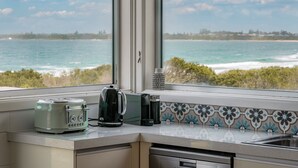 Une cuisine avec vue sur l’océan, un grille-pain, une bouilloire et une machine à café posés sur le plan de travail.