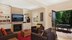 Un salon moderne doté d’une cheminée, de sièges confortables, d’un téléviseur et offrant une vue sur l’extérieur.