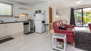 A modern apartment with a kitchen, a red leather sofa, and a dining area. - ALTONA GARDEN RETREAT (spreyton)