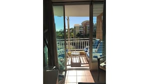 Enjoy the pool view from this balcony with a glass door leading to a sun lounger and table.