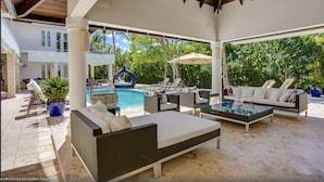 Un'area relax esterna coperta con poltrone, piscina e vasca idromassaggio.