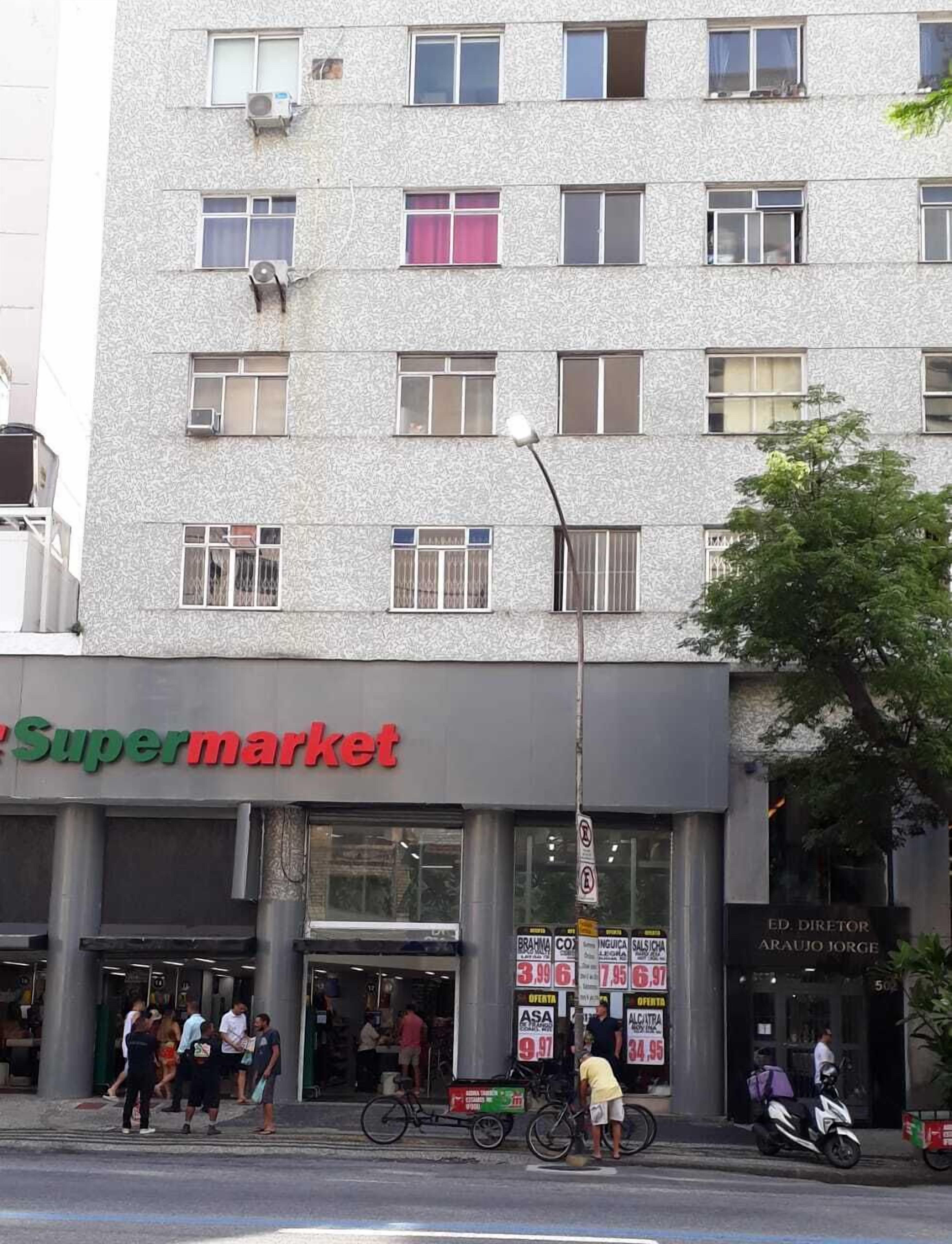 Ein mehrstöckiges Gebäude mit einem 'Supermarkt'-Schild im Erdgeschoss.