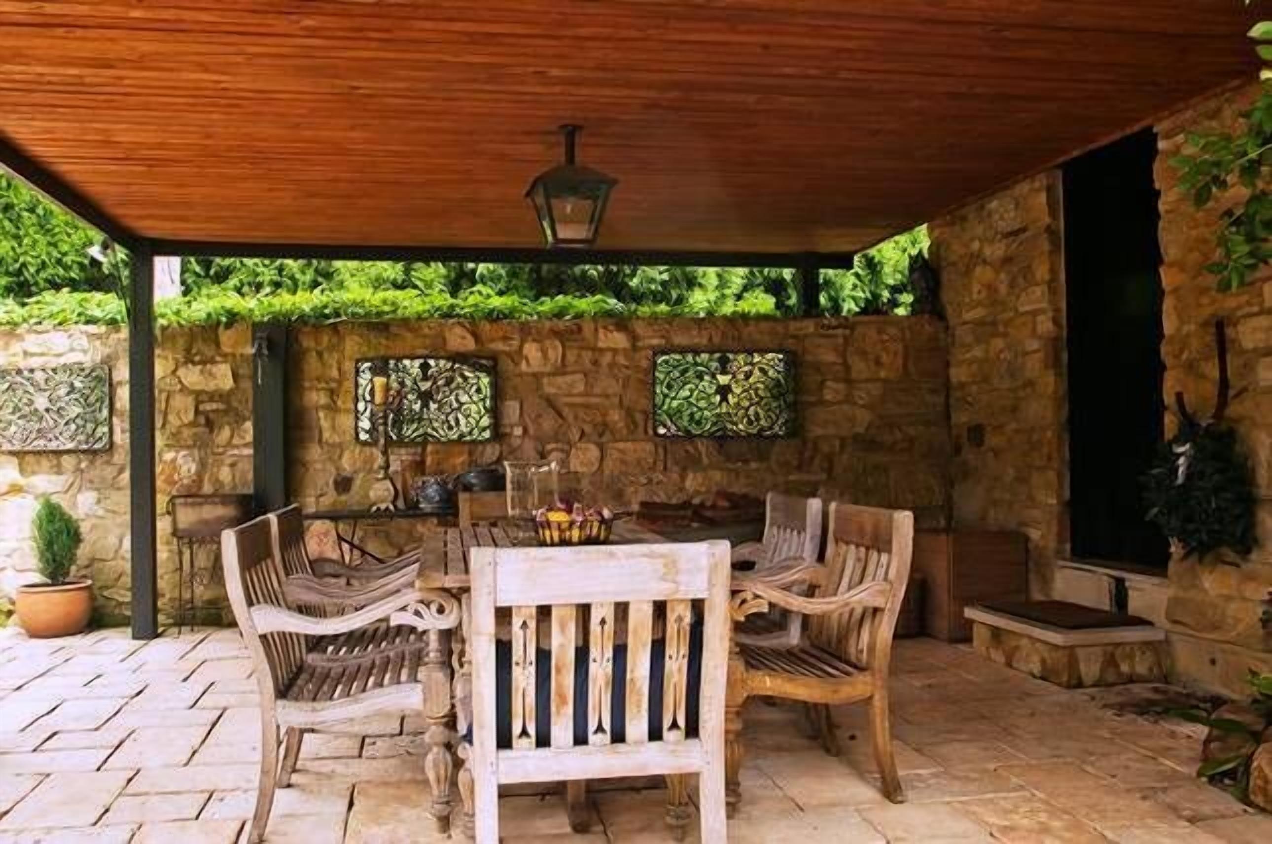 Une terrasse extérieure avec un mur en pierre, des meubles en bois et une lanterne.