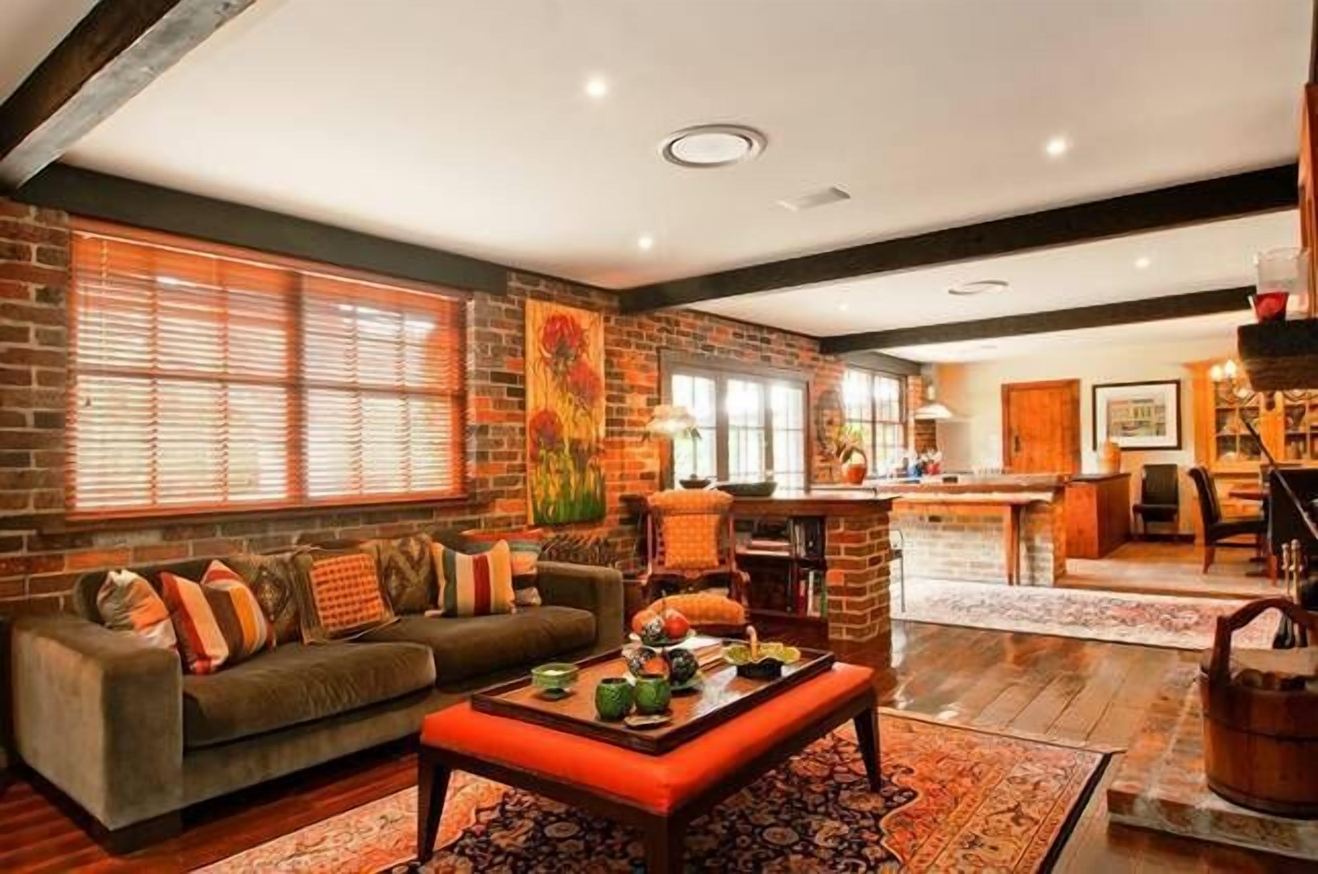 A cozy living room with a brick wall, a sofa, a coffee table, and a kitchen area in the background.