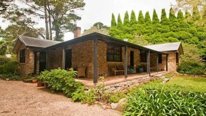 A stone house with a covered porch and a garden.