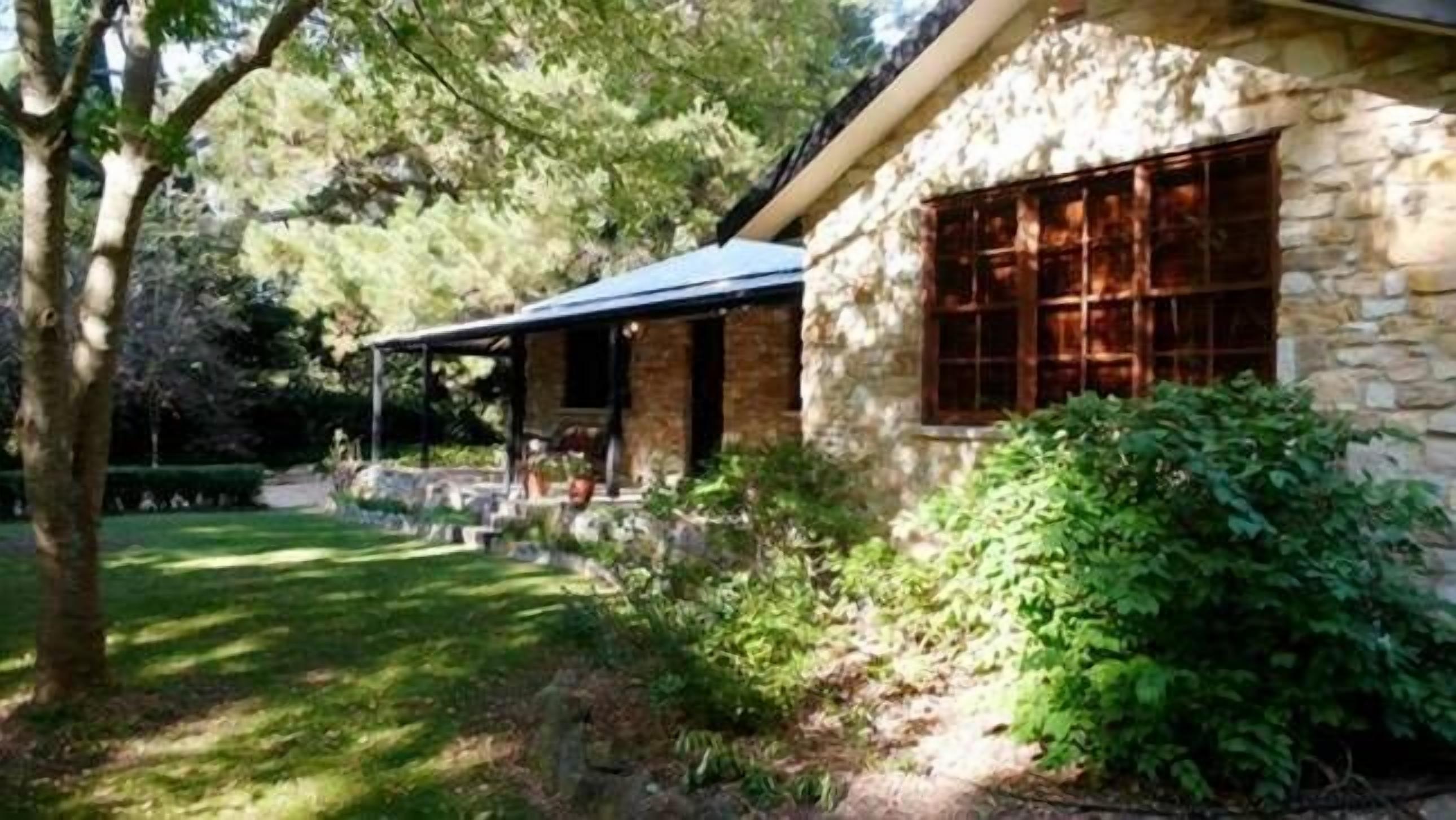 A stone house with a covered porch and a large window.