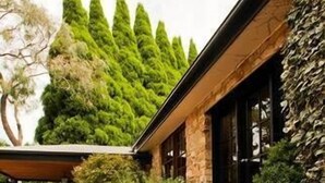 A stone building with a covered patio area, potted plants, and a stone wall.