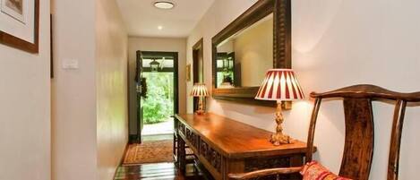 A hallway with a wooden dining table, chairs, and a large mirror on the wall.
