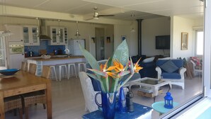 A modern kitchen with white cabinets, a blue tiled backsplash, and a dining area with wicker furniture. - "The Old School House" (Currarong)