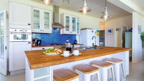 Eine moderne Küche mit weißen Schränken, einer blauen Spritzschutzwand und einer Holztischinsel mit Barhocker.