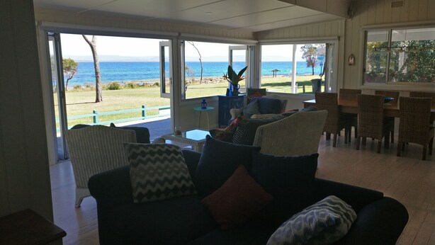A living room with a view of the sea, wicker furniture, and a dining area. - "The Old School House" (Currarong)