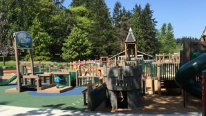 A playground with a slide, climbing structures, and a bench.
