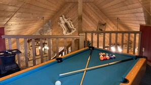 A pool table with balls and cues, a stone wall with a fur rug, and a wooden ceiling. - A+ Location 2 mi Pigeon Forge Pkwy,Not up Mtn, Hottub, Quiet,Private,SUPER CLEAN (Sevierville)