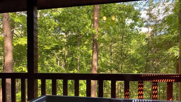 A hot tub with a view of a forested area through a wooden deck. - A+ Location 2 mi Pigeon Forge Pkwy,Not up Mtn, Hottub, Quiet,Private,SUPER CLEAN (Sevierville)