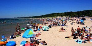 Ein voller Strand mit Menschen, die sich sonnen, schwimmen und Strandsonnenstühle benutzen.