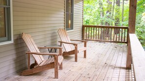 A wooden deck with two Adirondack chairs and a small table. - Hilltop Cottage in Pentwater Village (Pentwater)