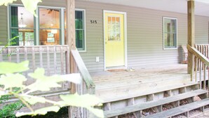 A house with a porch, a yellow door, and a number 515 on the wall. - Hilltop Cottage in Pentwater Village (Pentwater)