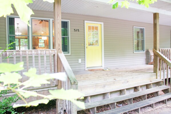 A house with a porch, a yellow door, and a number 515 on the wall.