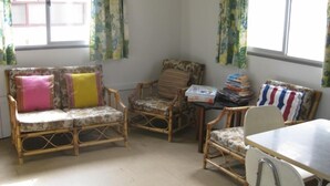 A room with a sofa, two chairs, a table, and a window with curtains.