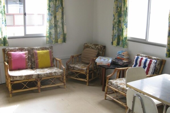 Une pièce comprenant un canapé, deux fauteuils, une table et une fenêtre avec des rideaux.