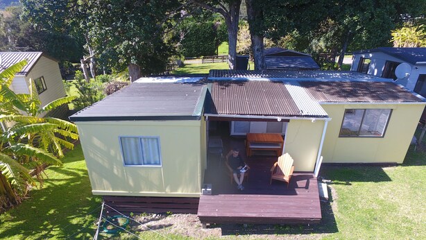 A small, single-story house with a porch, a satellite dish, and a lawn.