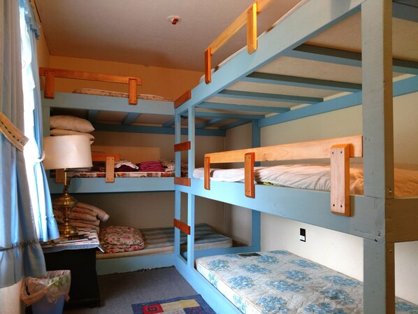 A bunk bed room with a desk and a lamp.