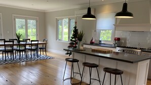 A modern kitchen with a central island, bar stools, and a dining area with a wooden table and chairs. - Marden Meadows - Luxury home in Kangaroo Valley (Kangaroo Valley)