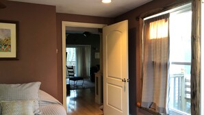 Un dormitorio con una cama, una puerta que da a un balcón y vistas al exterior.