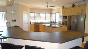 Una cocina con una isla grande, armarios de madera, un refrigerador y un microondas.