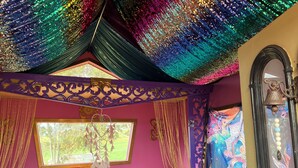 Una habitación con cabecera capitonada, un ventanal con vistas y un techo decorativo.