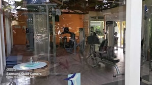 A gym with various exercise equipment, a glass wall, and a view of the outdoors.
