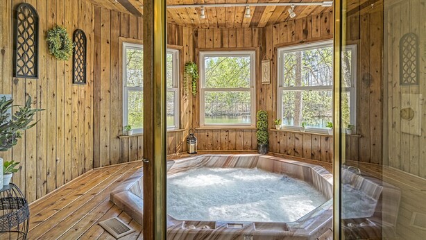 L’intérieur d’un chalet en bois, avec un jacuzzi, de grandes fenêtres et des murs en bois.
