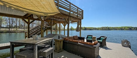 A wooden deck with outdoor furniture, a covered seating area, and a view of a lake.