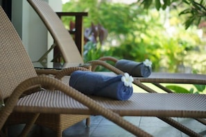 Wicker lounge chairs with rolled towels and a white flower.