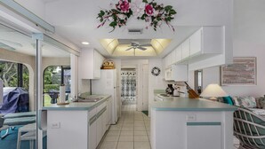 Cozinha moderna com armários brancos, uma ilha central e um ventilador de teto.
