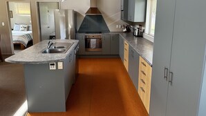 Cocina compacta con isla central, horno empotrado y muebles grises.