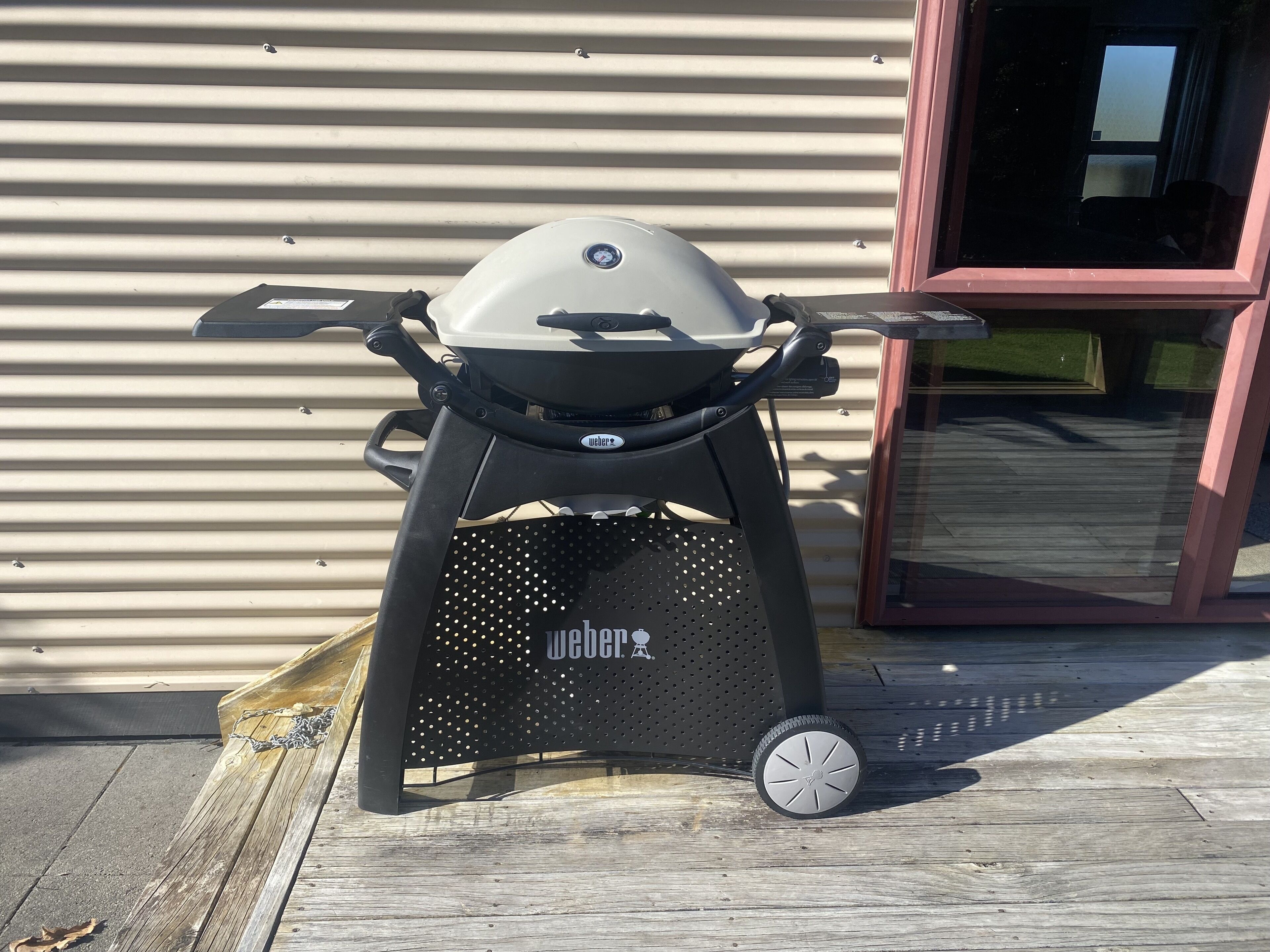 Un barbecue portable doté d’un logo, d’une façade noire perforée et d’une seule roue.