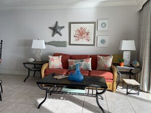 A living room with a sofa, coffee table, and two side tables with lamps. - Ocean Club of Deerfield Beach (Deerfield Beach)