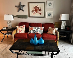 A living room with a red sofa, three blue vases on a black coffee table, and decorative pillows.