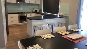 A modern kitchen with white cabinets, a black countertop, and a central island with bar stools. - Beach gemPhillip Island (sunderland bay)