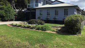 A two-story house with a balcony, surrounded by well-maintained lawns and shrubs. - Beach gemPhillip Island (sunderland bay)