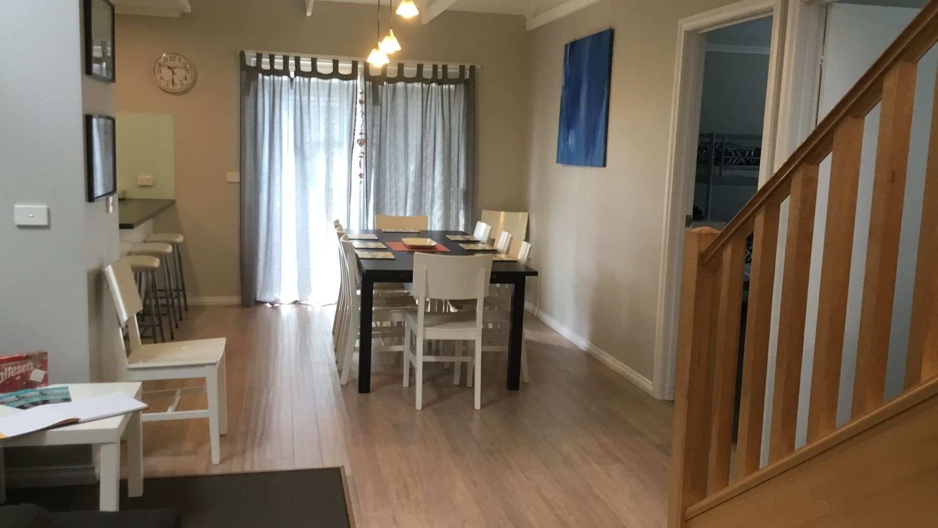 Un coin repas avec une table et des chaises, un escalier et une horloge au mur.