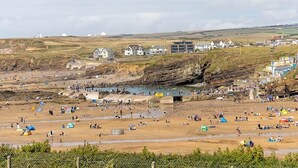 A coastal beach with tents and people, rocky cliffs, and buildings in the background. - Cosy rural barn retreat for couples near stunning Cornish coast (Woolley, Bude)