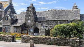 A stone building with a steeply pitched roof, a chimney, and a small arched entrance. - Cosy rural barn retreat for couples near stunning Cornish coast (Woolley, Bude)