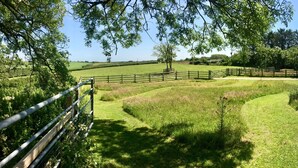 A rural landscape with a fenced area, a white building, and a clear sky. - Cosy rural barn retreat for couples near stunning Cornish coast (Woolley, Bude)