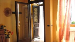 A room with a wooden door, a small table with a bowl, and a potted plant with flowers. - Pella: Pella, Lake of Orta: house on the Lake,fantastic view (Pella)