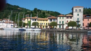 A marina with boats docked, buildings with traditional architecture, and a hill in the background. - Pella: Pella, Lake of Orta: house on the Lake,fantastic view (Pella)
