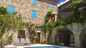 A stone building with a swimming pool, outdoor seating, and climbing plants. - Close to Uzès, House with character beautifully restored (Saint-Jean-De-Ceyrargues)
